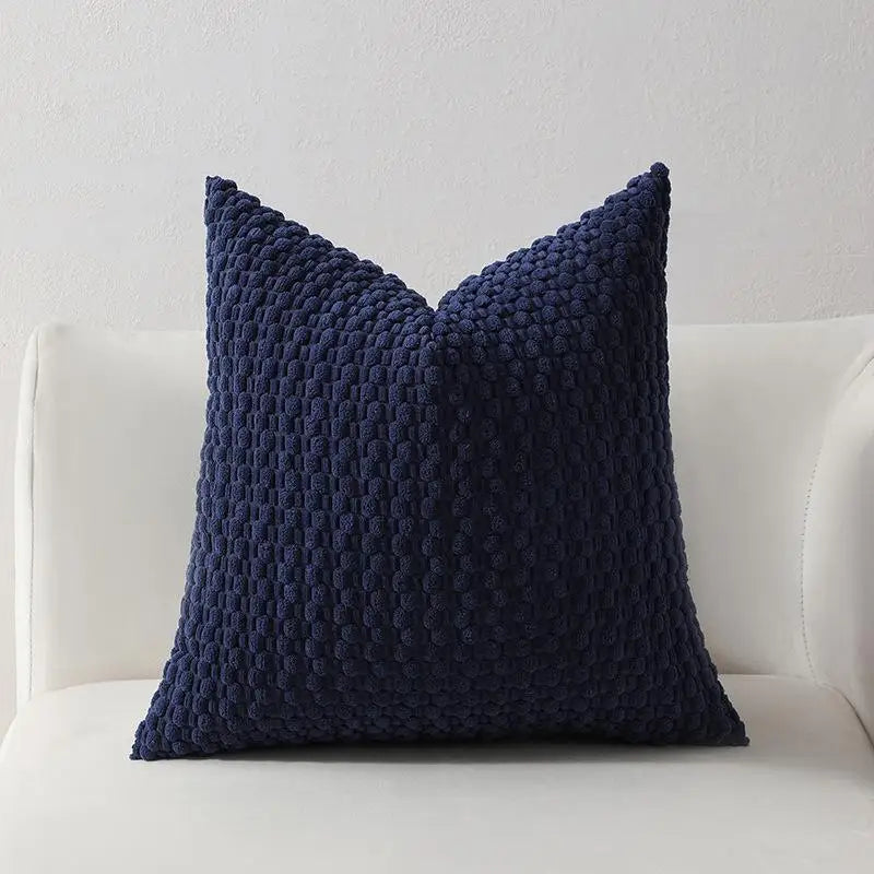 Housse coussin velours posée sur un canapé naturel