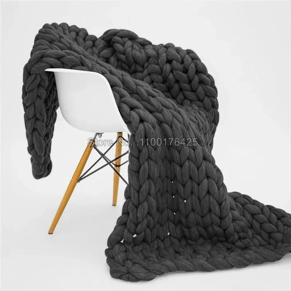Couverture grosse maille dépliée sur un canapé blanc