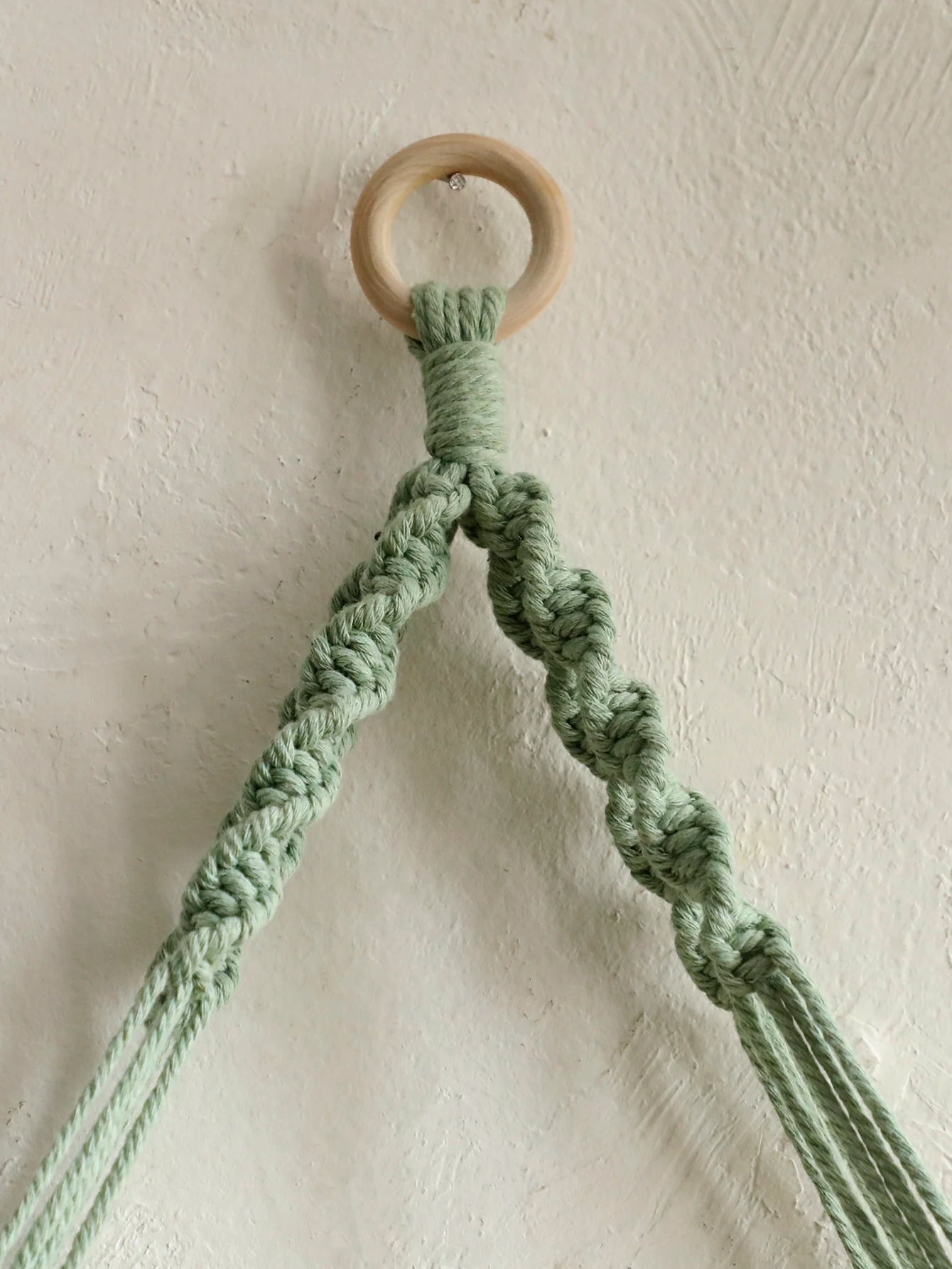 Étagère macramé pompons installée sur un mur blanc